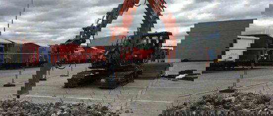 Excavator breaking out concrete yard with hydraulic breaker at Europa Worldwide Group site in Ascot