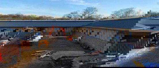 Tracked excavator digging foundation trenches at Langshot Stud equestrian facility in Surrey