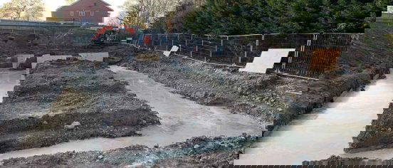 Freshly poured concrete infill within foundation trenches on a construction site at Bracknell, surrounded by excavated soil and temporary fencing